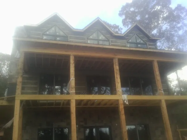 Dormers and porch framing on a large log home under construction — Roof Coating work by our crew in Kennard